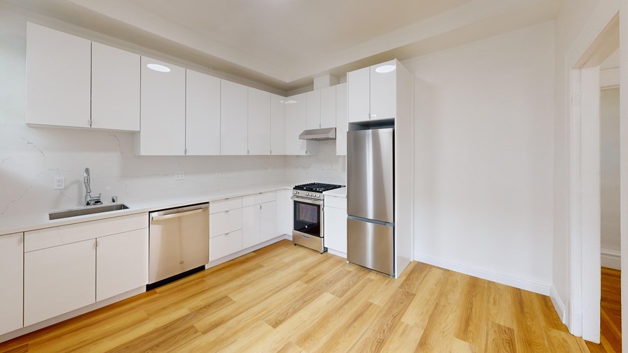 A kitchen with white cabinets and a wooden floor.